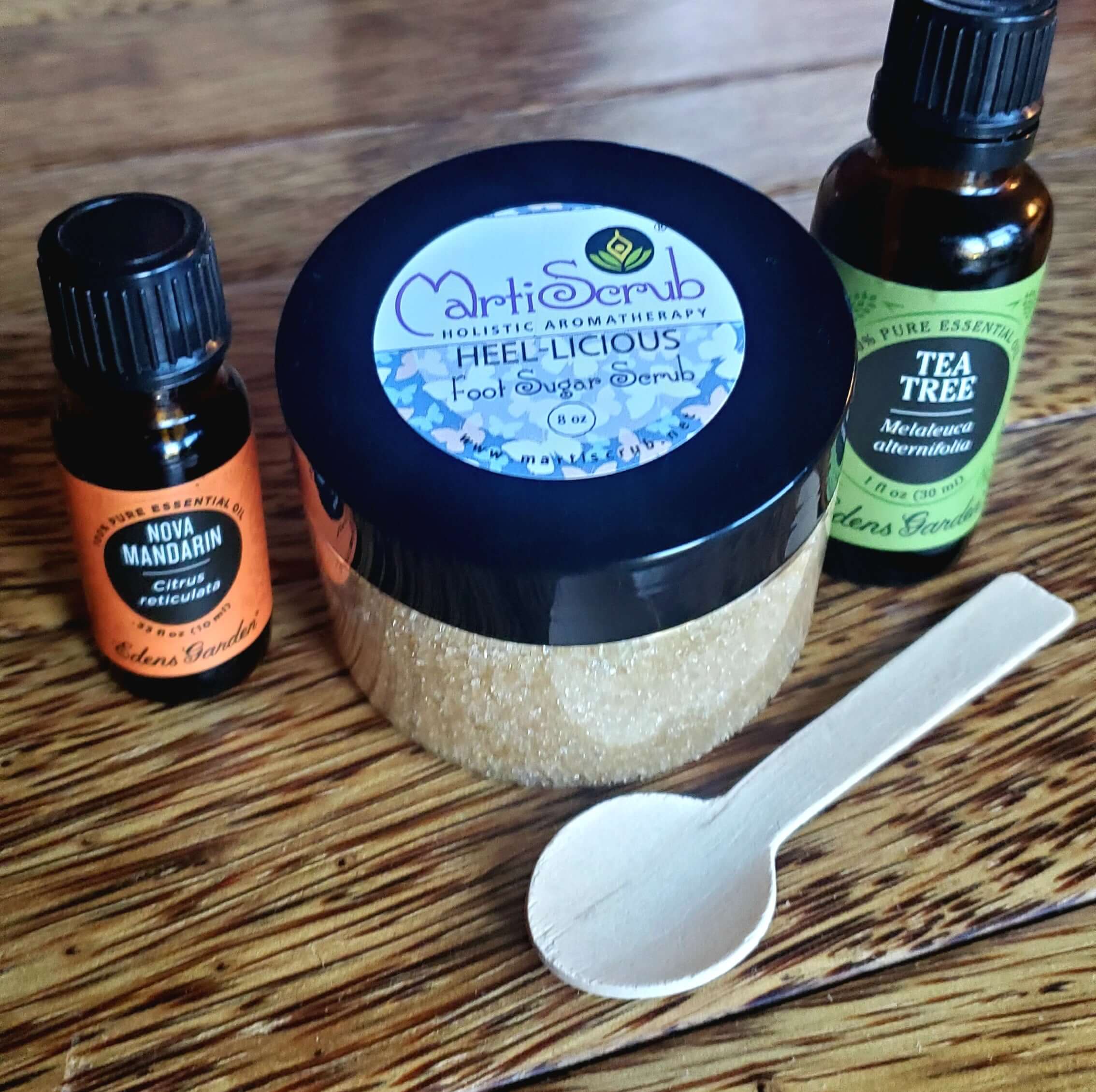 Organic foot sugar scrub with essential oils, featuring peppermint, lemon, and tea tree, on a wooden background.