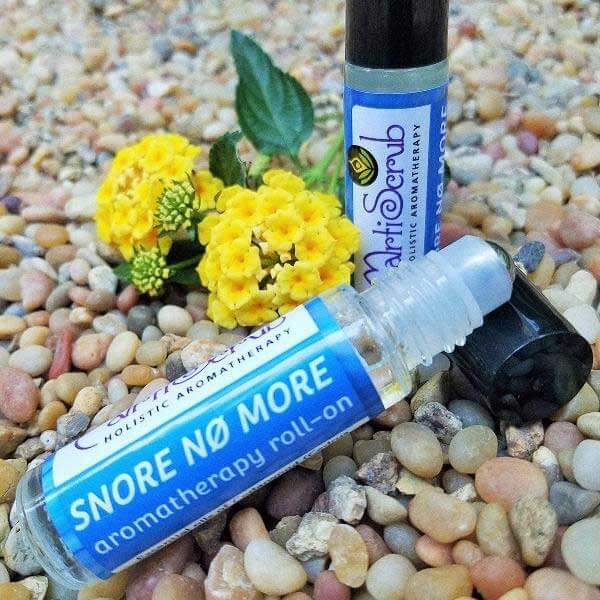 Anti-snoring essential oil roll-on beside flowers and stones, promoting restful sleep with natural ingredients.