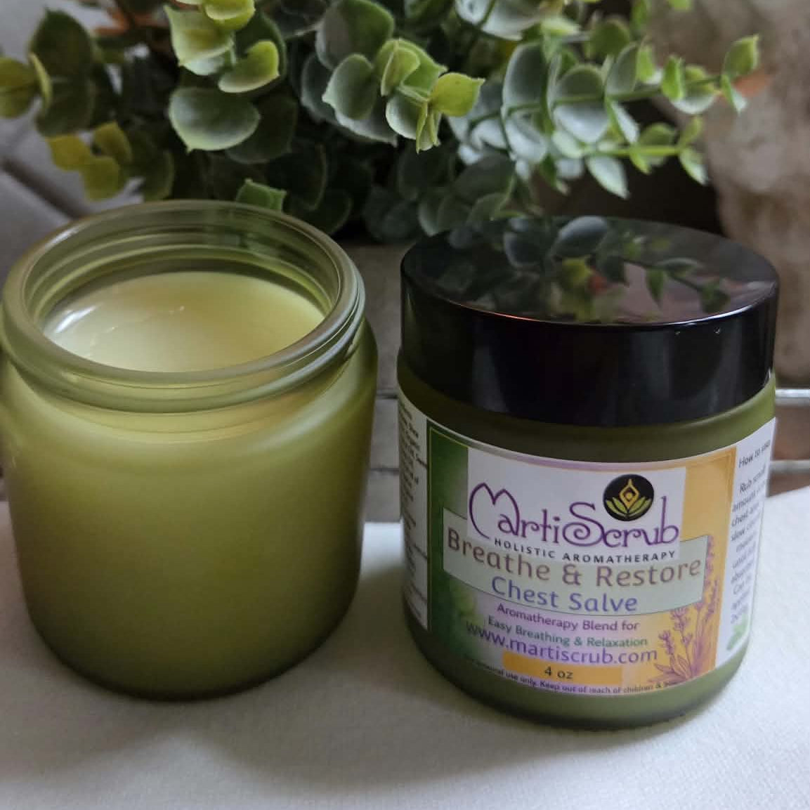 MartiScrub Breathe & Restore Chest Salve in a jar next to a green candle, promoting relaxation and breathing.