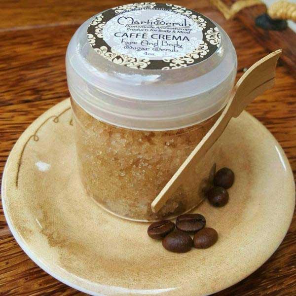 Aromatherapy coffee sugar scrub Caffè Crema in a 4 oz jar with a wooden spoon and coffee beans on a plate.