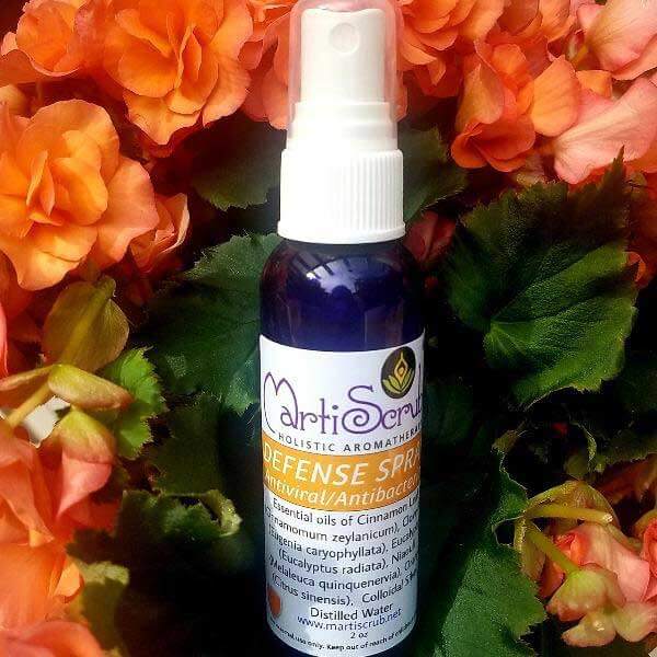 Defense Room Spray bottle surrounded by vibrant orange flowers, featuring essential oil benefits for cleaning and freshness.