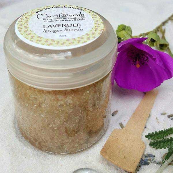 Lavender sugar scrub in jar with wooden scoop, surrounded by flowers, showcasing aromatherapy benefits.