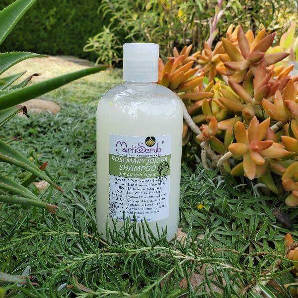Natural Rosemary Jojoba Shampoo bottle surrounded by greenery, ideal for revitalizing all hair types and soothing the scalp.