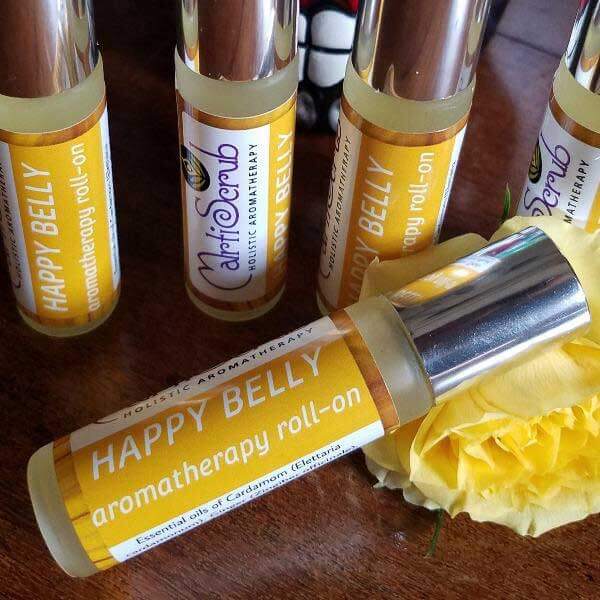 Happy Belly digestive support essential oil roll-on bottle with yellow label, surrounded by other aromatherapy products.
